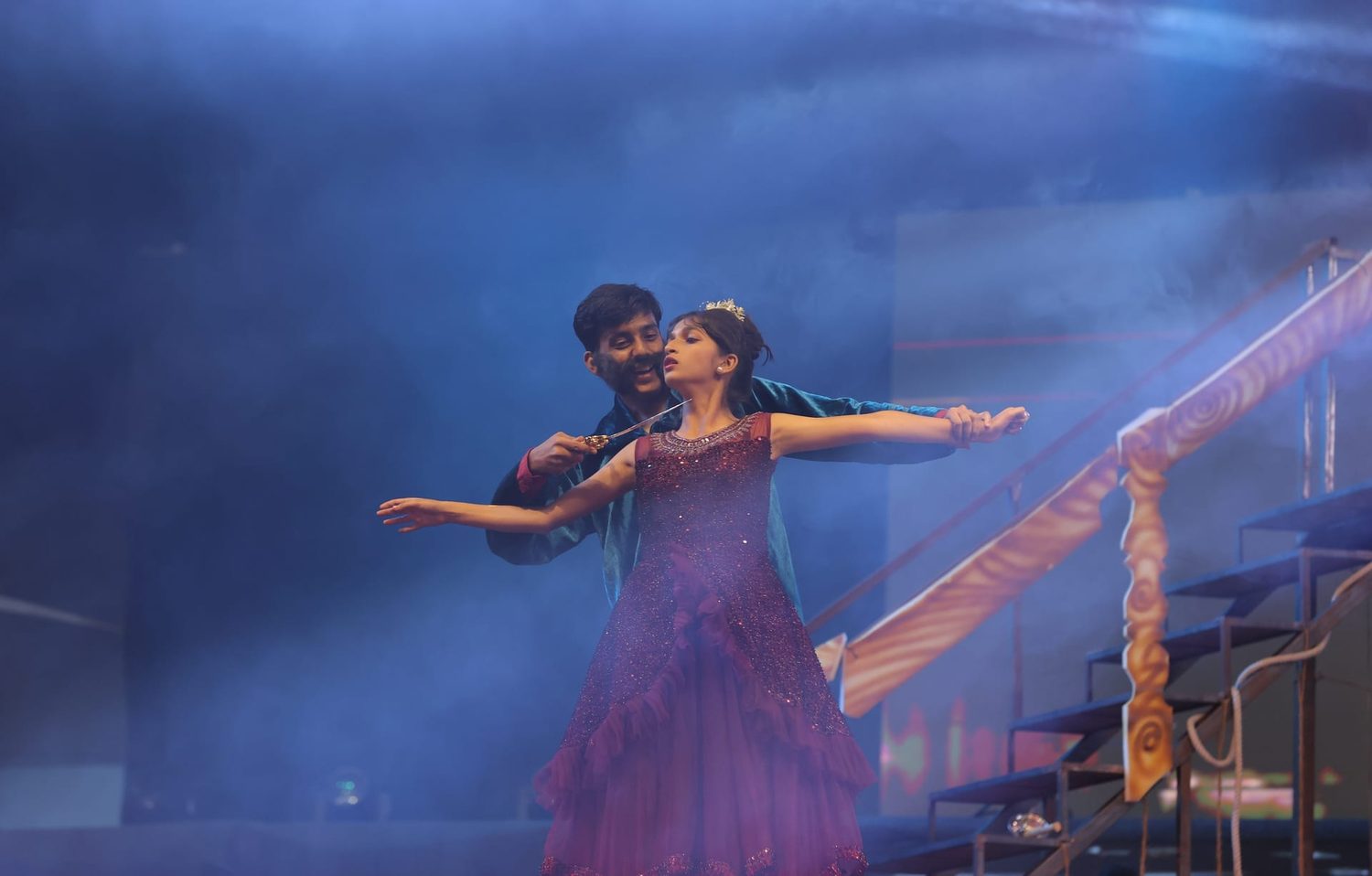 Students performing on a professionally lit stage during a school annual day